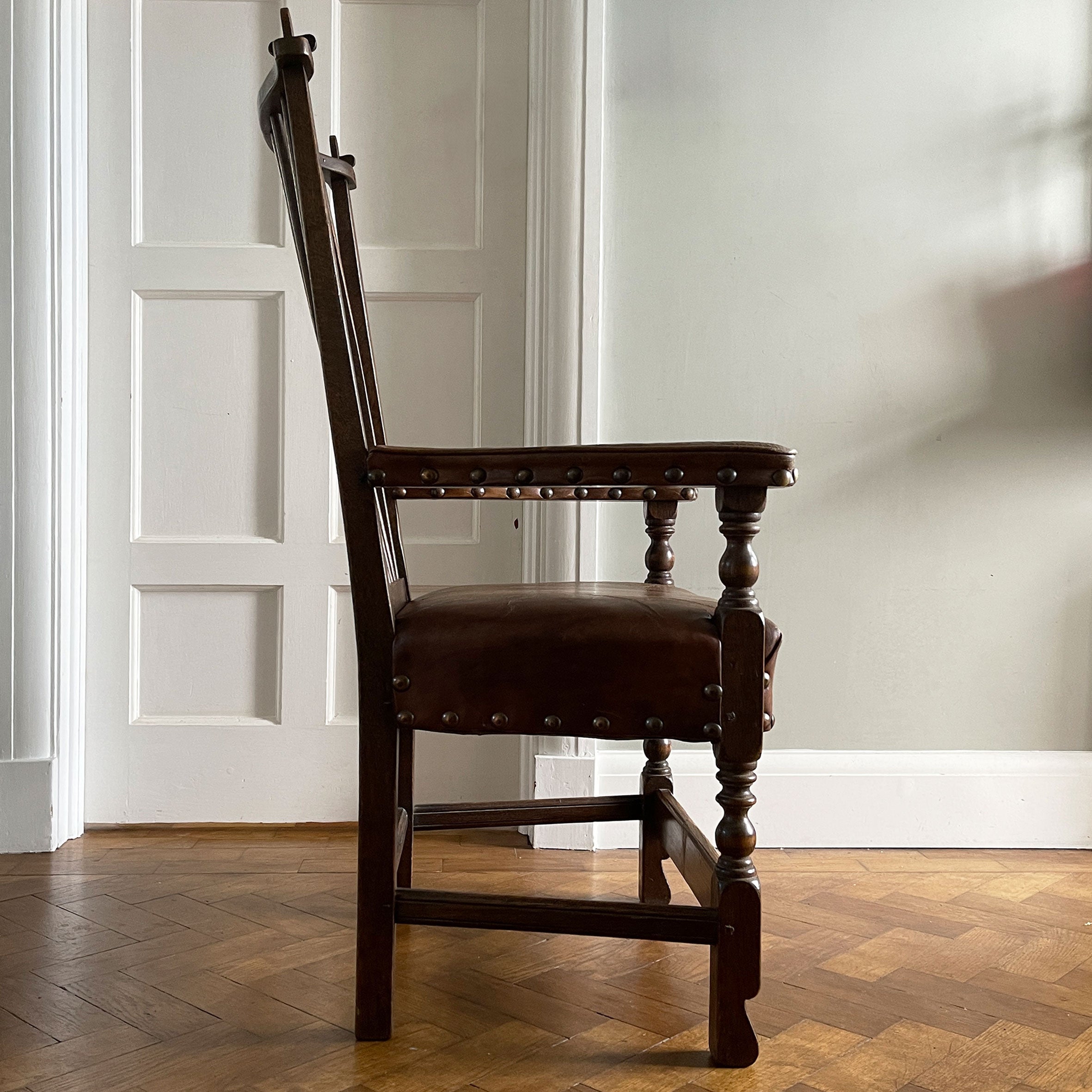 A super solid oak Arts and Crafts styled Carver Chair by the master furniture maker Rupert Griffiths. The style is known as 'Monastic' with this being a Swiss Stick back. The chair has its original leather seat and arms with big old brass studs holding it all in place. The frame is of oak and jointed with oak pegs - SHOP NOW - www.intovintage.co.uk