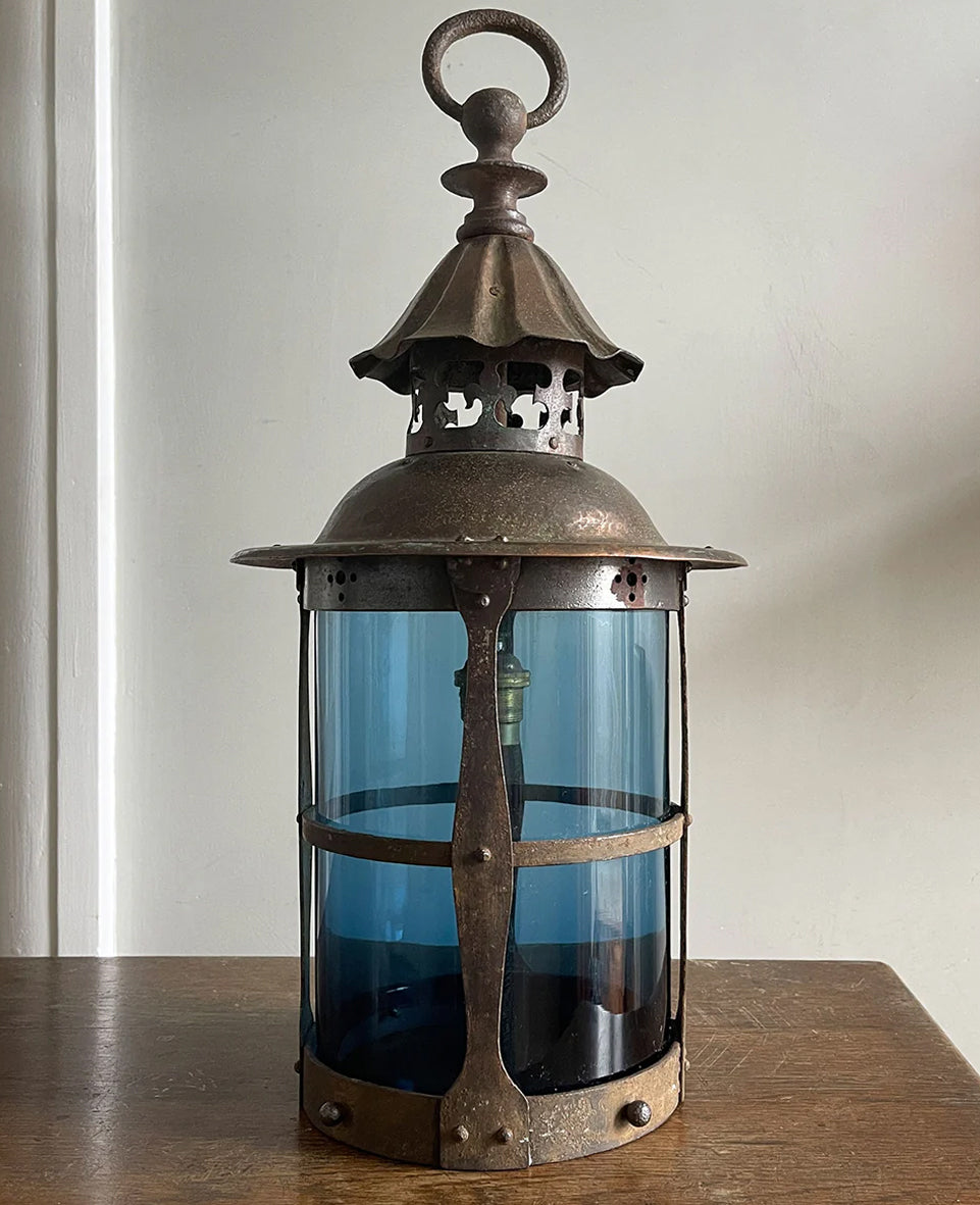 A large Arts & Crafts Hall Lantern. Hand beaten copper top with fleur de lis detailing, smithed iron shade cage Hall lantern with original mouth blown petrol blue glass. Elegant form, scale and colour - SHOP NOW - www.intovintage.co.uk