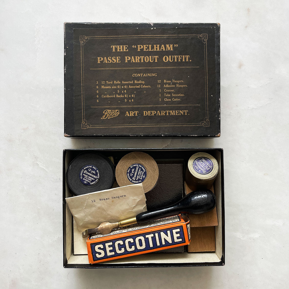 A vintage Pelham Passe Partout picture framing kit from Boots. contents include a rather nifty Glass Cutter, 3 Rolls of Picture Gummed Picture Binding Tape, a Boxed Tube of Seccotine Adhesive, Brass Picture Hangers, Adhesive Hangers, Razor Blade, Creasing Blocks and a selection of Mounting Cards and Paper - SHOP NOW - www.intovintage.co.uk