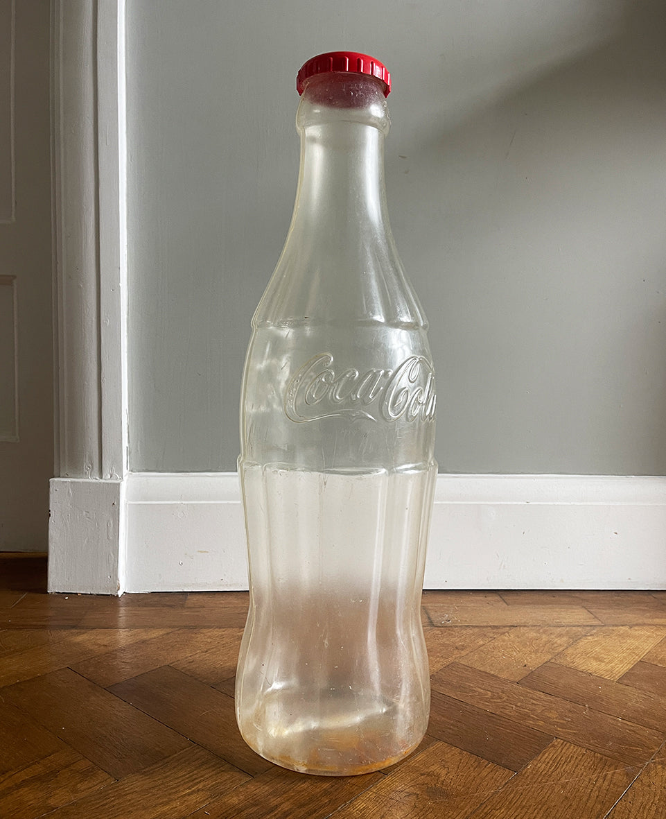A Very Large Vintage Coke Bottle made from a clear plastic with a red plastic cap lid that has a slot in it so that you can collect your loose change - SHOP NOW - www.intovintage.co.uk