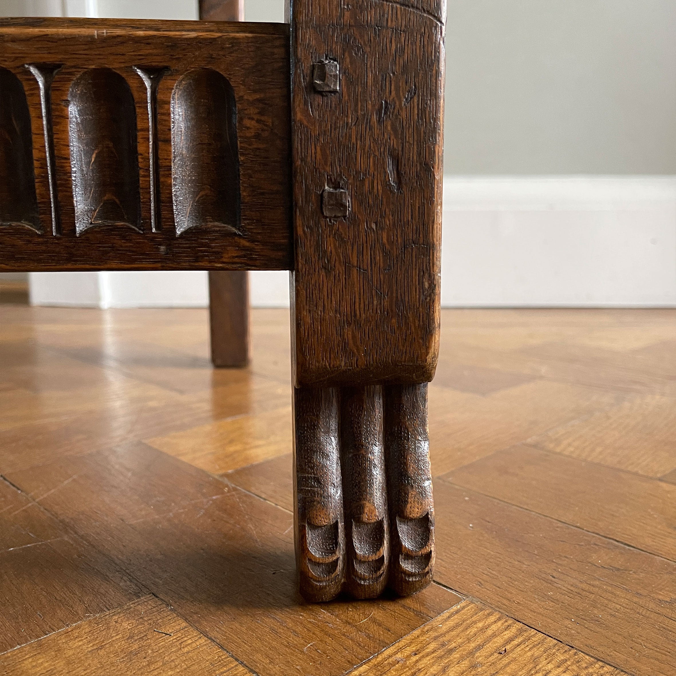 A super solid oak Arts and Crafts styled Carver Chair by the master furniture maker Rupert Griffiths. The style is known as 'Monastic' with this being a Swiss Stick back. The chair has its original leather seat and arms with big old brass studs holding it all in place. The frame is of oak and jointed with oak pegs - SHOP NOW - www.intovintage.co.uk