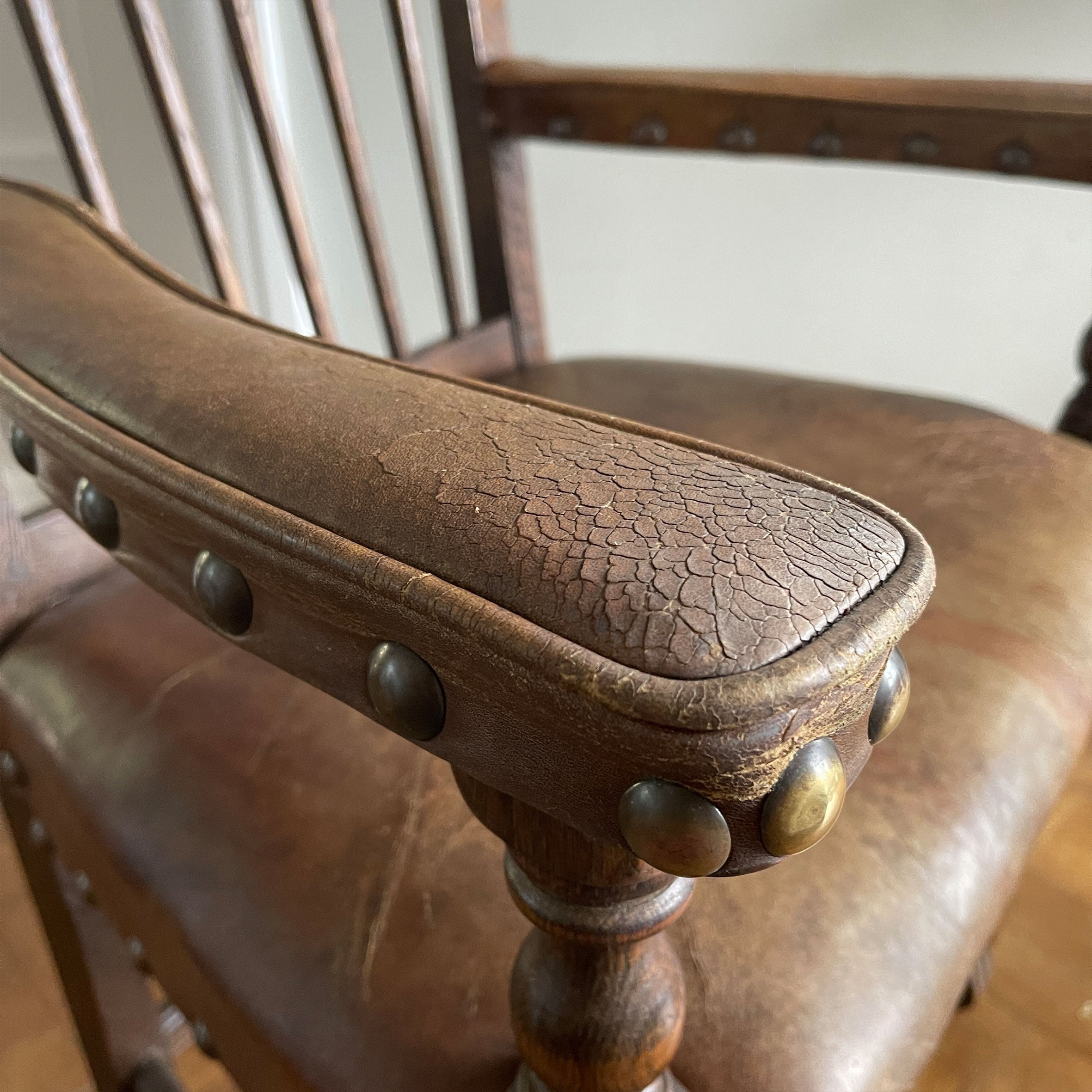 A super solid oak Arts and Crafts styled Carver Chair by the master furniture maker Rupert Griffiths. The style is known as 'Monastic' with this being a Swiss Stick back. The chair has its original leather seat and arms with big old brass studs holding it all in place. The frame is of oak and jointed with oak pegs - SHOP NOW - www.intovintage.co.uk