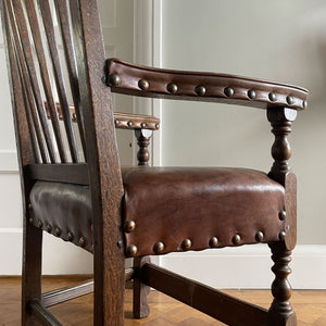 A super solid oak Arts and Crafts styled Carver Chair by the master furniture maker Rupert Griffiths. The style is known as 'Monastic' with this being a Swiss Stick back. The chair has its original leather seat and arms with big old brass studs holding it all in place. The frame is of oak and jointed with oak pegs - SHOP NOW - www.intovintage.co.uk