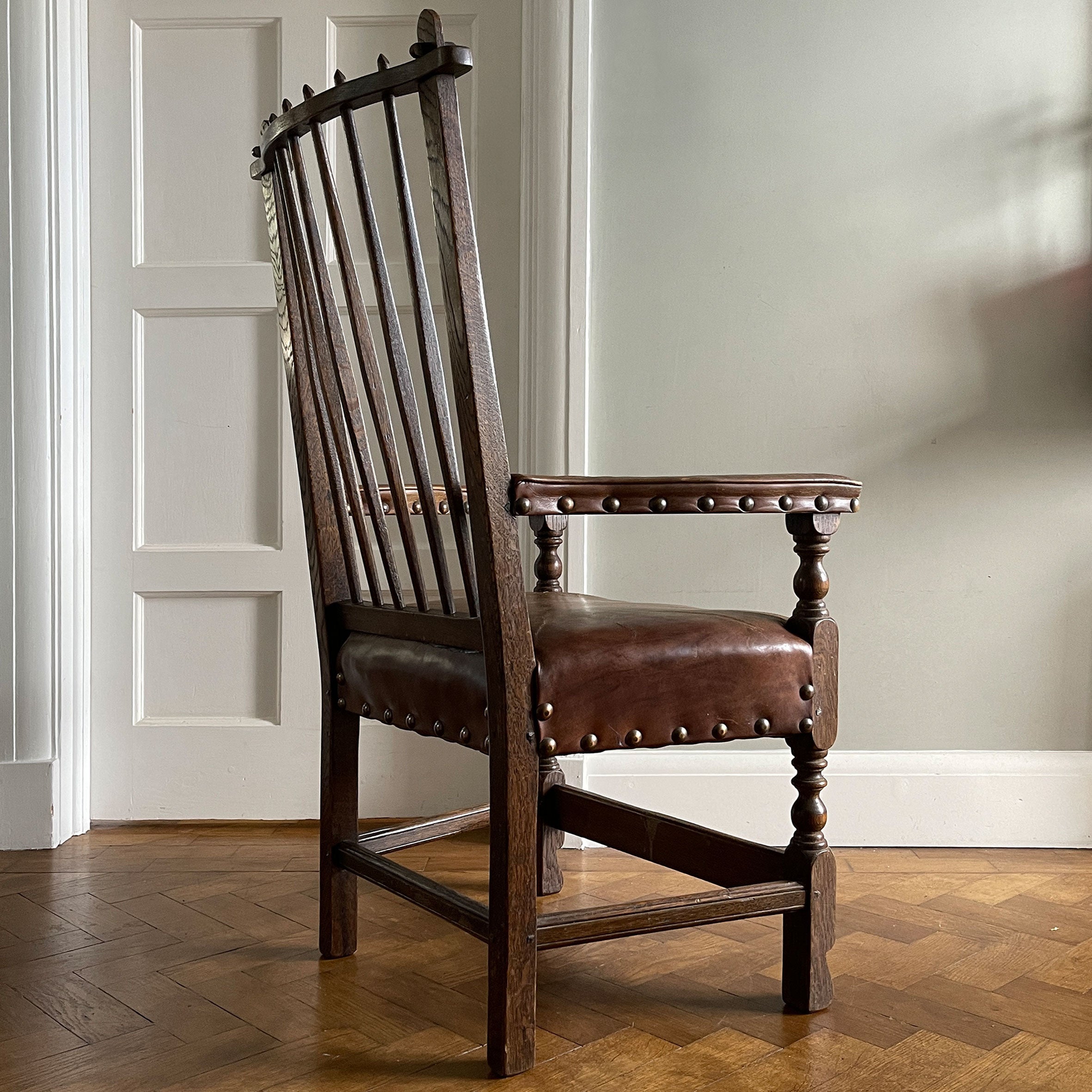 A super solid oak Arts and Crafts styled Carver Chair by the master furniture maker Rupert Griffiths. The style is known as 'Monastic' with this being a Swiss Stick back. The chair has its original leather seat and arms with big old brass studs holding it all in place. The frame is of oak and jointed with oak pegs - SHOP NOW - www.intovintage.co.uk