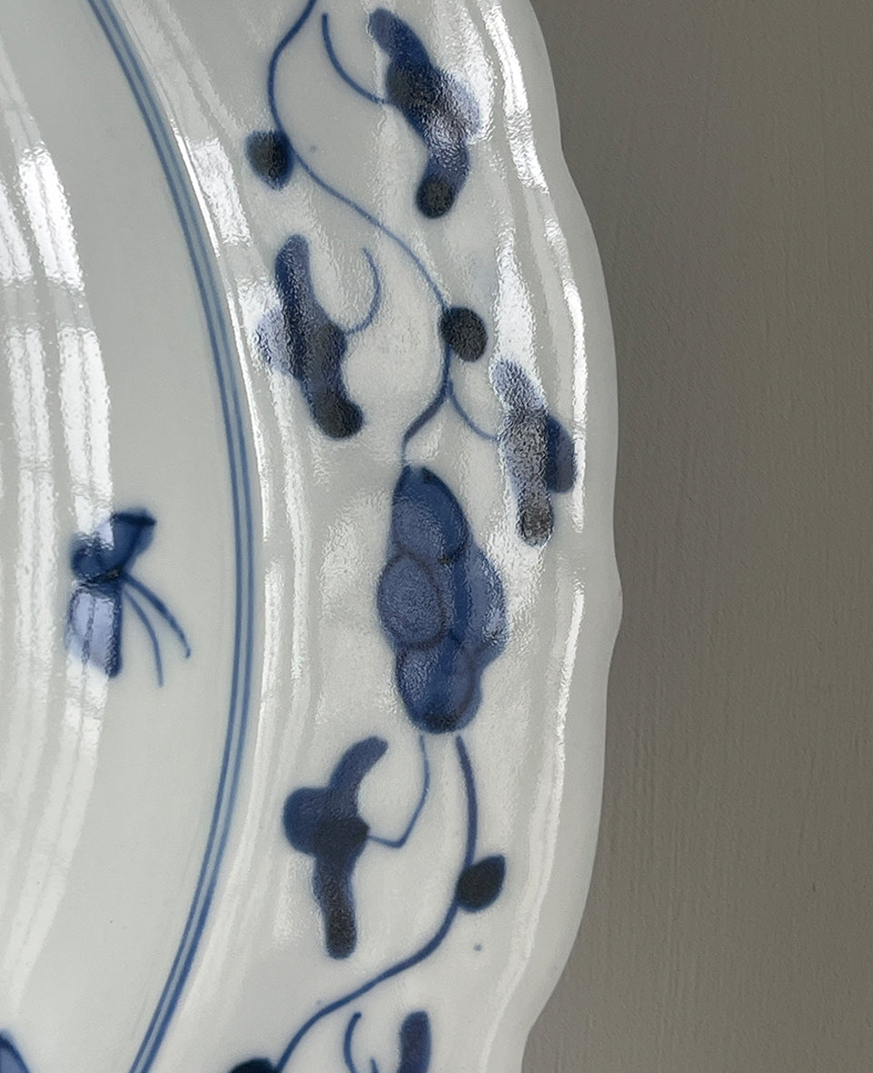 A large Oriental Imari scolloped edged plate with colourful hand painted depictions of Chrysanthemum flowers, fans, birds and cherry blossom. The underside sees a freeze of blue lilies - SHOP NOW - www.intovintage.co.uk