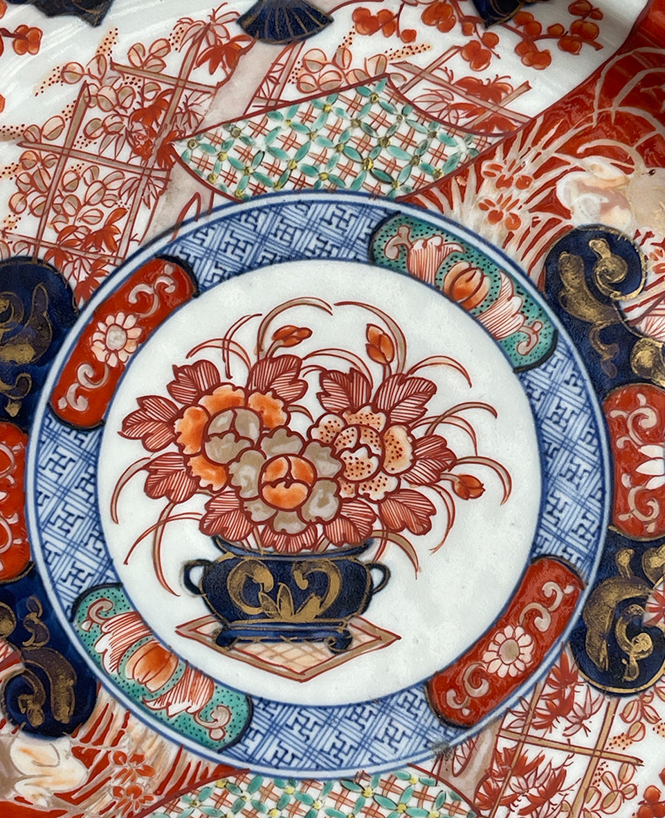 A large Oriental Imari scolloped edged plate with colourful hand painted depictions of Chrysanthemum flowers, fans, birds and cherry blossom. The underside sees a freeze of blue lilies - SHOP NOW - www.intovintage.co.uk