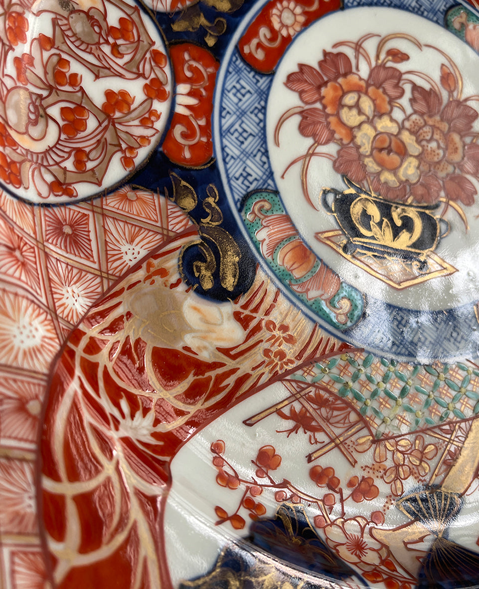 A large Oriental Imari scolloped edged plate with colourful hand painted depictions of Chrysanthemum flowers, fans, birds and cherry blossom. The underside sees a freeze of blue lilies - SHOP NOW - www.intovintage.co.uk