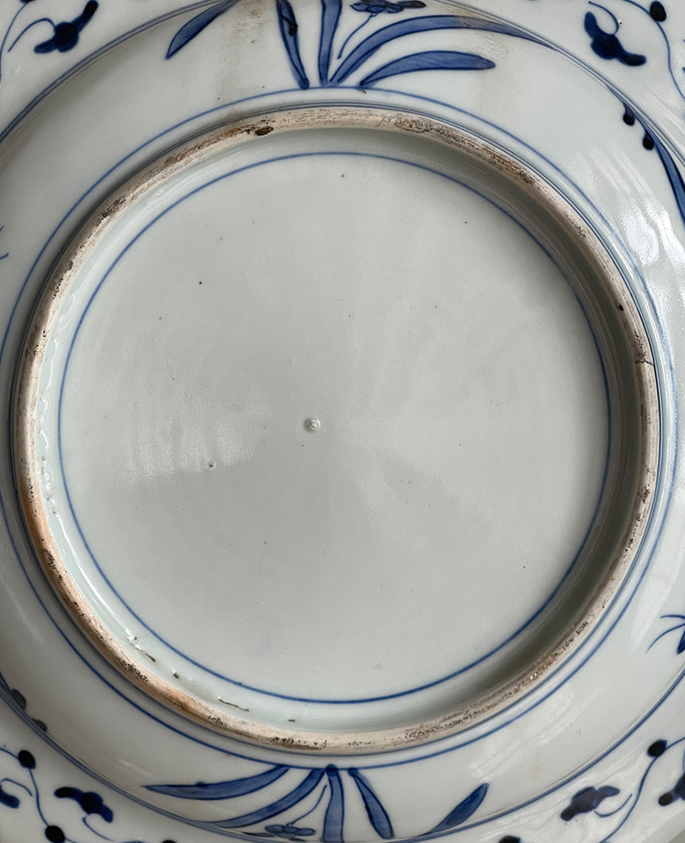 A large Oriental Imari scolloped edged plate with colourful hand painted depictions of Chrysanthemum flowers, fans, birds and cherry blossom. The underside sees a freeze of blue lilies - SHOP NOW - www.intovintage.co.uk