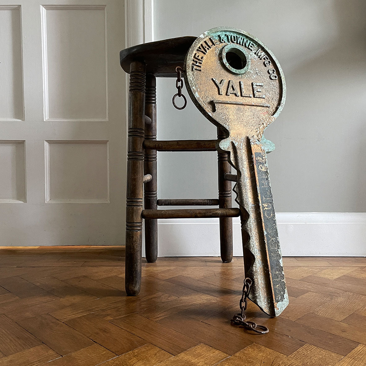 A large cast metal oversized Yale key with its original hanging chains, used as an advertisement display in locksmith shops and ironmongers. It has its original gilt paint finish that has weathered over the yeas to achieve the most amazing patinated finish. Hangs horizontal when suspended on its chains - SHOP NOW - www.intovintage.co.uk