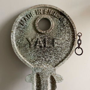 A large cast metal oversized Yale key with its original hanging chains, used as an advertisement display in locksmith shops and ironmongers. It has its original gilt paint finish that has weathered over the yeas to achieve the most amazing patinated finish. Hangs horizontal when suspended on its chains - SHOP NOW - www.intovintage.co.uk