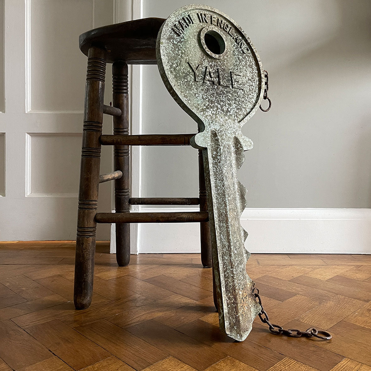 A large cast metal oversized Yale key with its original hanging chains, used as an advertisement display in locksmith shops and ironmongers. It has its original gilt paint finish that has weathered over the yeas to achieve the most amazing patinated finish. Hangs horizontal when suspended on its chains - SHOP NOW - www.intovintage.co.uk