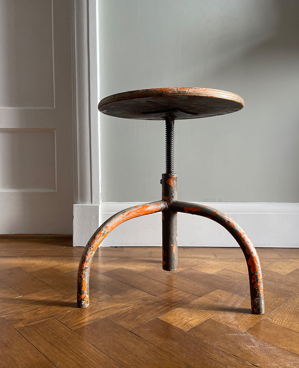 A Vintage Metal and Wood Stool set on 3 legs with an adjustable seat that when rotated adjusts the height of the seat. Great age related wear with worn orange paint - SHOP NOW - www.intovintage.co.uk
