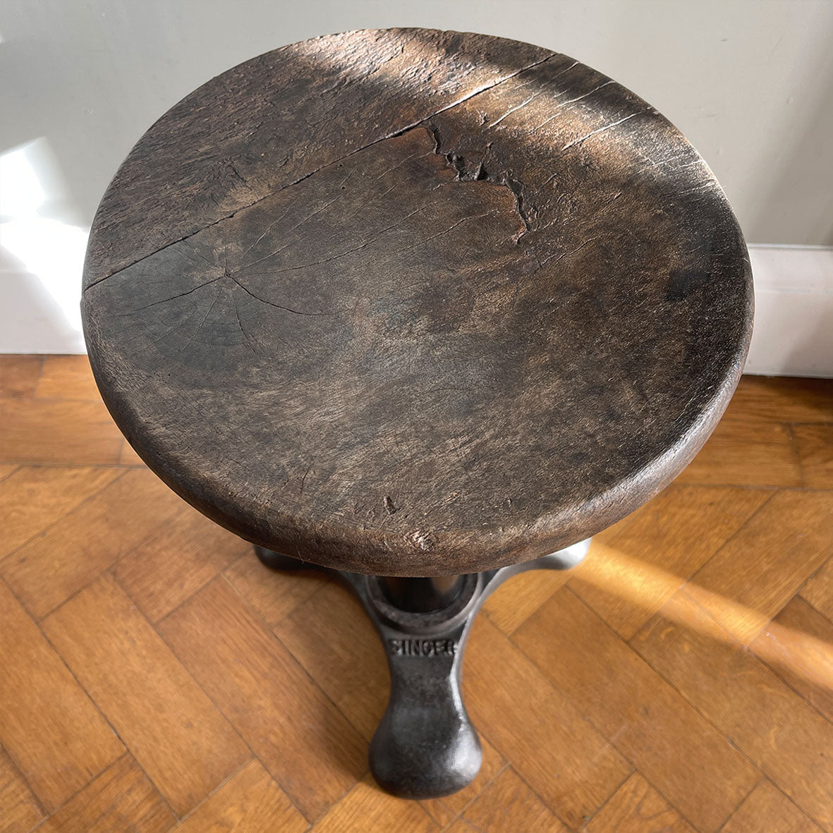 An Antique Singer Work Stool. It has a cast iron tripod base with the SINGER brand mark, a black painted steel stem and original turned wooden button seat. The wood shows fantastic age related patina. A great looking stool that would compliment any setting - SHOP NOW - www.intovintage.co.uk