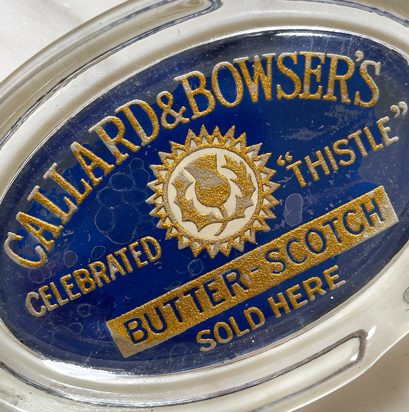 A Glass Callard & Bowser's Celebrated Thistle Butter Scotch Advertising Ashtray with nice gold and blue typography and thistle graphic - SHOP NOW - www.intovintage.co.uk