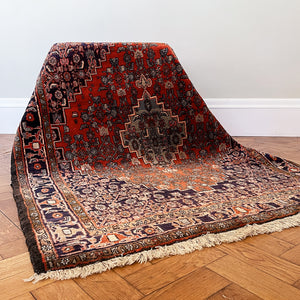A beautiful, rich dark blue and red handmade Persian Heriz rug in wool. The overall condition is very good. With one pale blue central medallion decoration on a red diamond background framed by deep blue. A good practical size - SIZE: (L) 150cm   (W) 115cm - SHOP NOW www.intovintage.co.uk