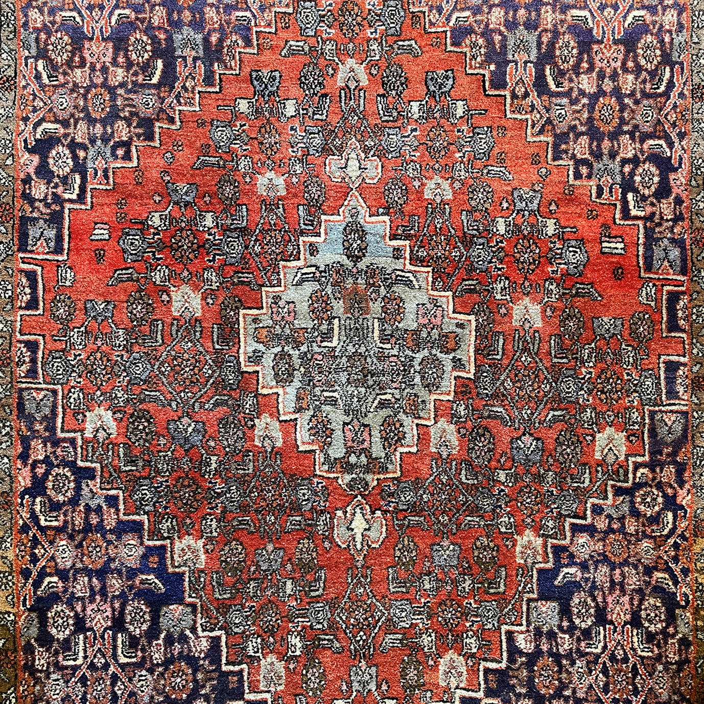 A beautiful, rich dark blue and red handmade Persian Heriz rug in wool. The overall condition is very good. With one pale blue central medallion decoration on a red diamond background framed by deep blue. A good practical size - SIZE: (L) 150cm   (W) 115cm - SHOP NOW www.intovintage.co.uk