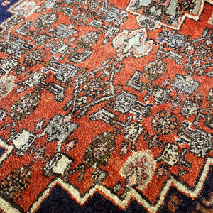 A beautiful, rich dark blue and red handmade Persian Heriz rug in wool. The overall condition is very good. With one pale blue central medallion decoration on a red diamond background framed by deep blue. A good practical size - SIZE: (L) 150cm   (W) 115cm - SHOP NOW www.intovintage.co.uk