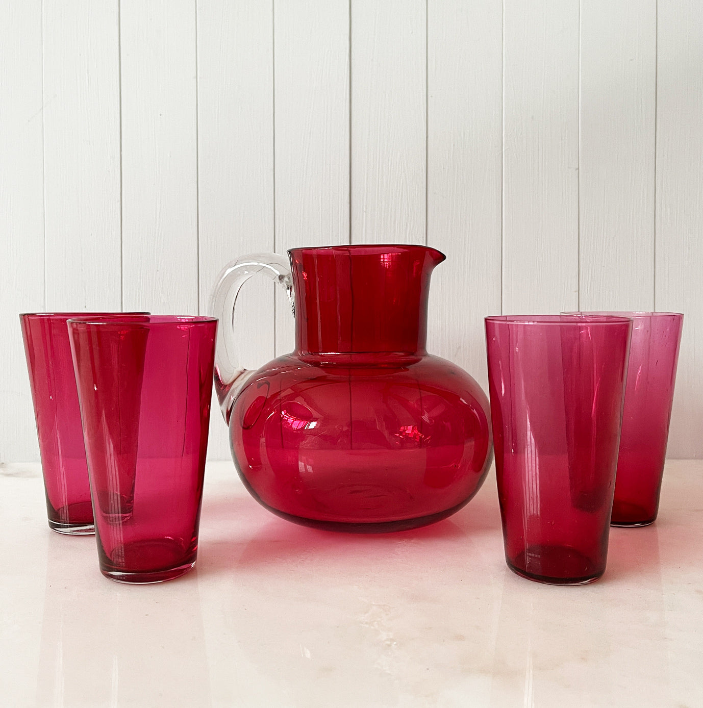 A beautiful Victorian hand blown cranberry glass water jug and glass set, comprising a rounded shaped jug with clear glass handle and four fine tumblers of tapering form. All in excellent condition - SHOP NOW - www.intovintage.co.uk