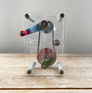 A Vintage Mechanical Teaching Aid that shows the mechanics of chained gears. Turning the little handle rotates a cog connected to a mini chain that in turn, turns another larger cog which rotates a green arrow - SHOP NOW - www.intovintage.co.uk
