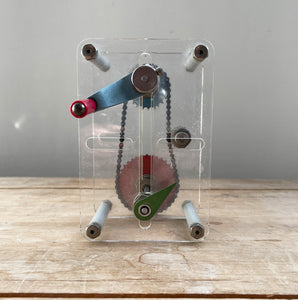 A Vintage Mechanical Teaching Aid that shows the mechanics of chained gears. Turning the little handle rotates a cog connected to a mini chain that in turn, turns another larger cog which rotates a green arrow - SHOP NOW - www.intovintage.co.uk