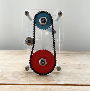A Vintage Mechanical Teaching Aid that shows the mechanics of chained gears. Turning the little handle rotates a cog connected to a mini chain that in turn, turns another larger cog which rotates a green arrow - SHOP NOW - www.intovintage.co.uk