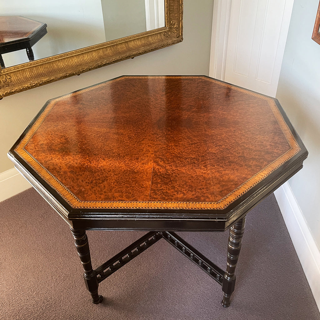 A Victorian marquetry & ebonised octagonal centre table in the Aesthetic manner by Alexander Mackenzie & Co, Glasgow.The top sees a rich burr wood veneer edged with fine blond wood marquetry, whilst underneath sees four turned ebonised legs with gold painted detailing and crossed bobbin stretchers - SHOP NOW - www.intovintage.co.uk
